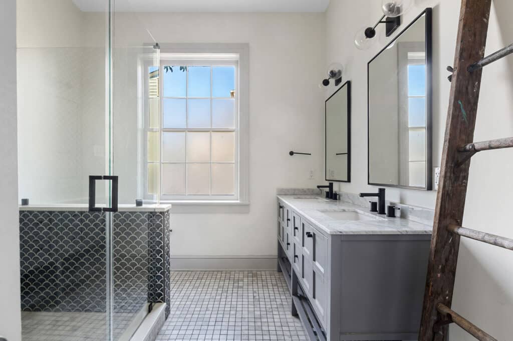 Modern bathroom with a double-sink vanity, twin rectangular mirrors, black fixtures, a glass-enclosed shower, and a wooden ladder by the wall.