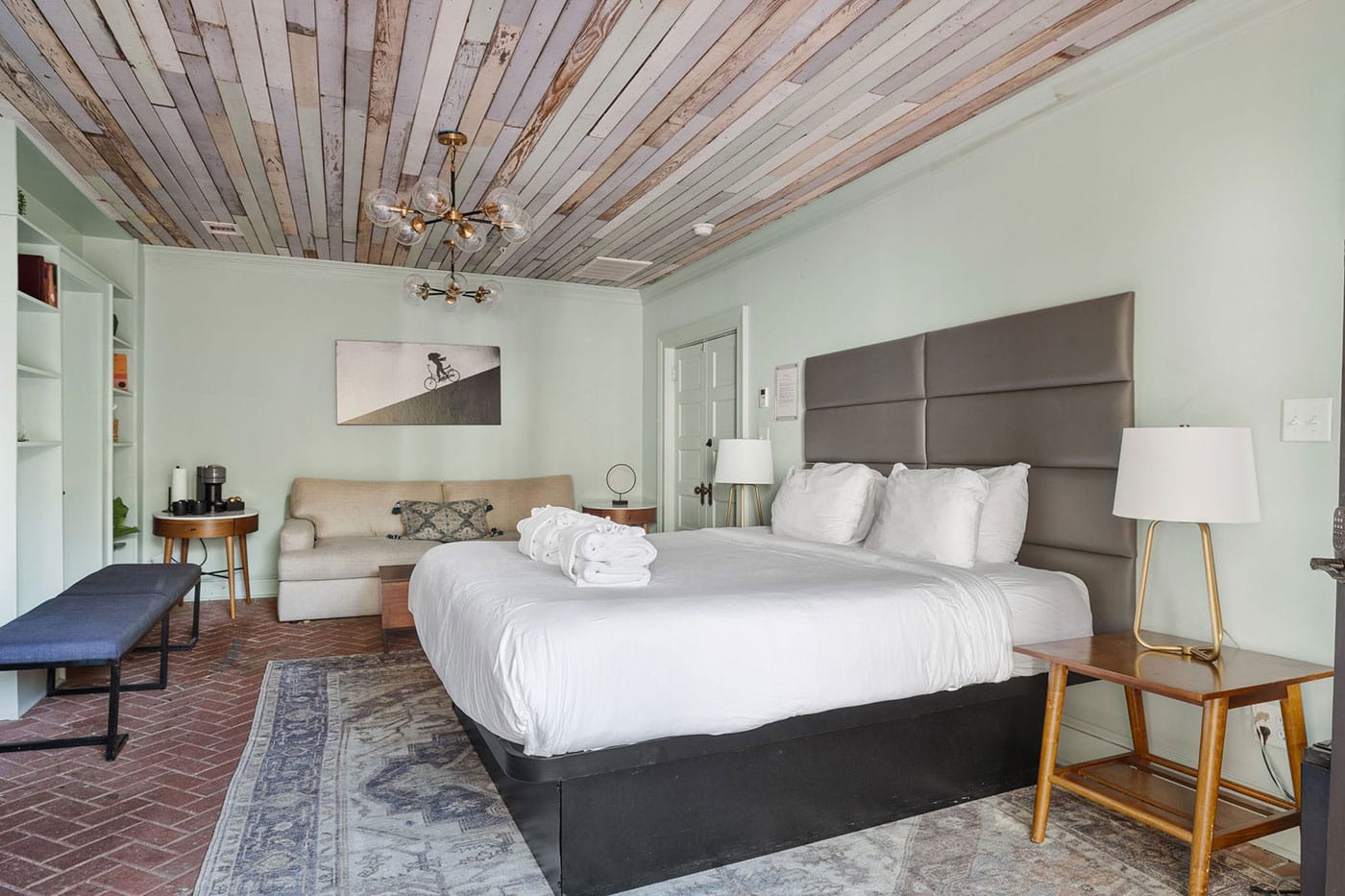 King bed with a gray upholstered headboard, white bedding, and matching bedside lamps in a bright bedroom.