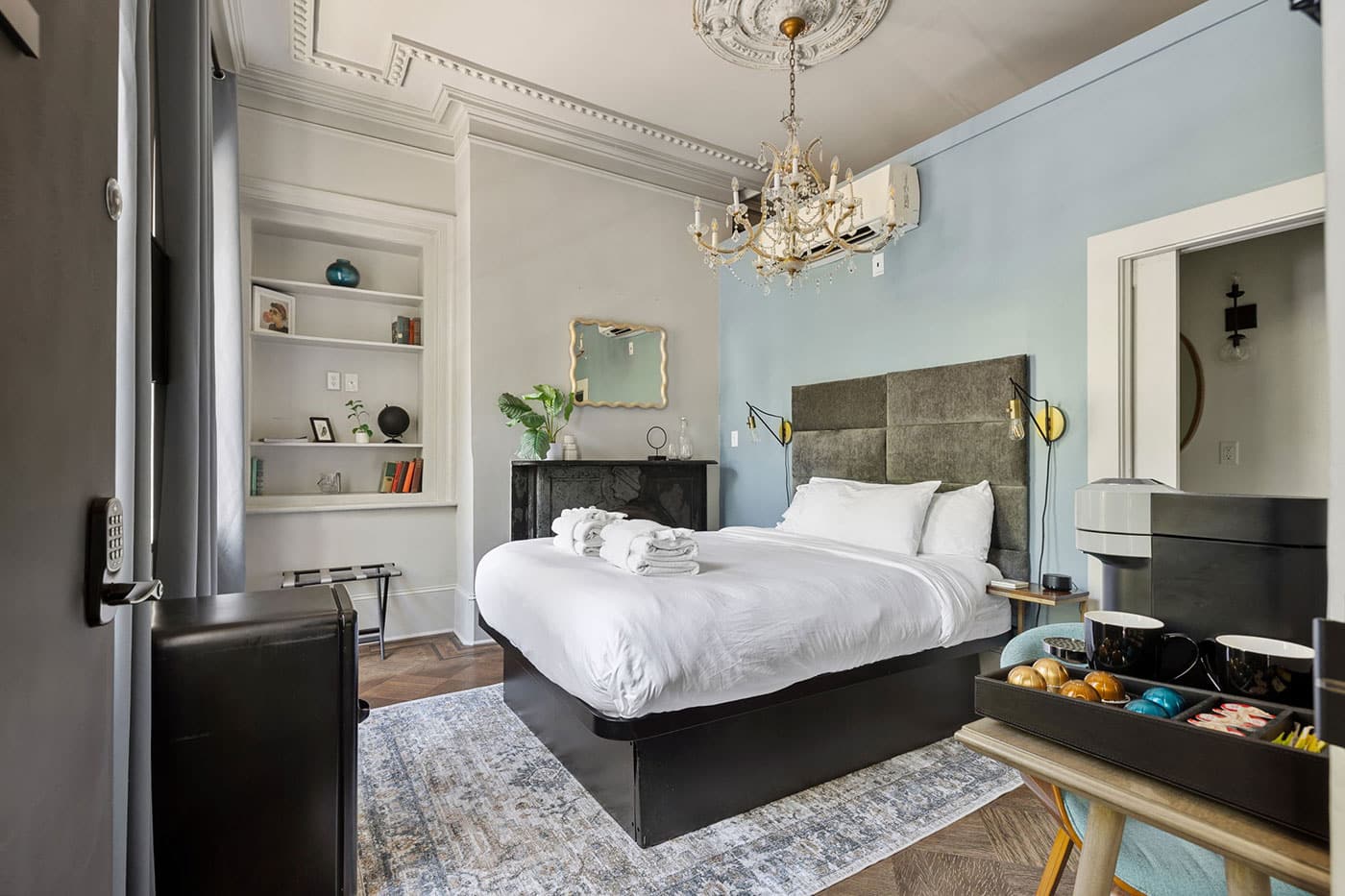 Luxurious bedroom with white bedding, upholstered headboard, chandelier, and built-in shelves.